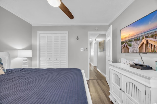 bedroom with ornamental molding, dark wood-type flooring, ceiling fan, and a closet