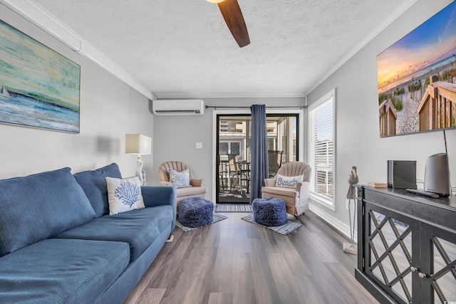 living room featuring wood-type flooring, an AC wall unit, ornamental molding, and a textured ceiling