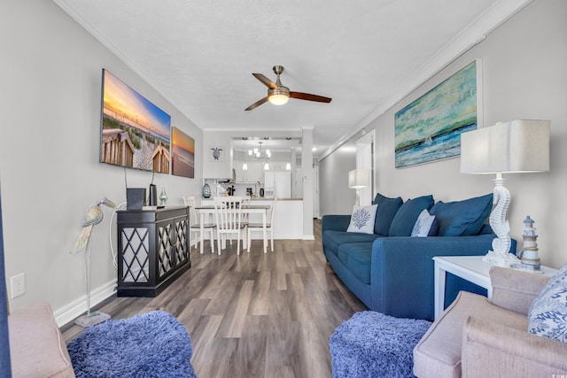 living room featuring hardwood / wood-style flooring, ornamental molding, ceiling fan with notable chandelier, and a textured ceiling