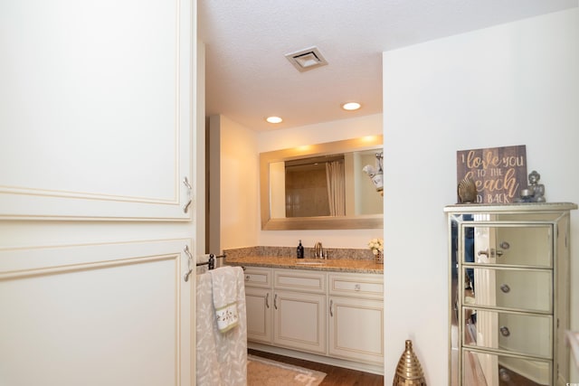 bathroom with hardwood / wood-style floors, vanity, and a textured ceiling