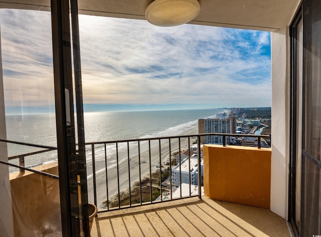 balcony with a water view and a view of the beach