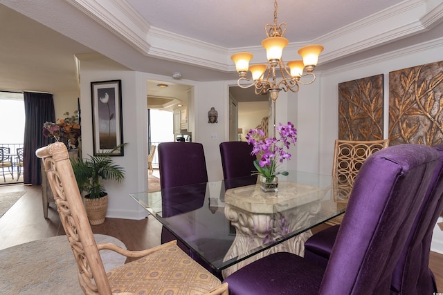 dining area with a raised ceiling, crown molding, hardwood / wood-style floors, and a notable chandelier