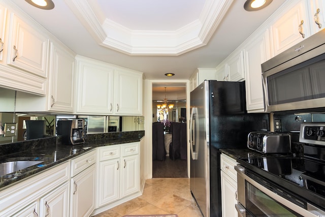 kitchen with crown molding, appliances with stainless steel finishes, a tray ceiling, a notable chandelier, and white cabinetry