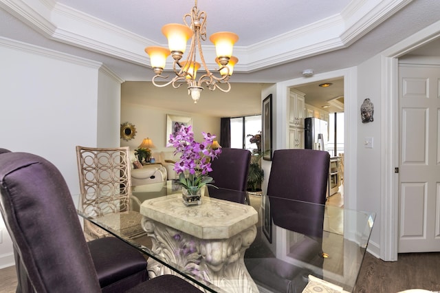 dining space featuring ornamental molding, dark wood-type flooring, a tray ceiling, and a notable chandelier