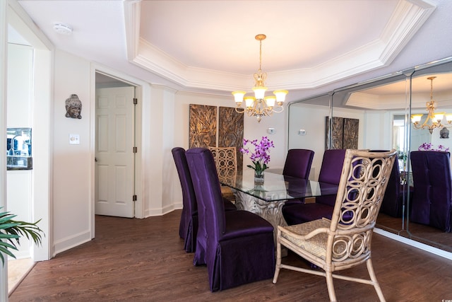 dining space with crown molding, dark wood-type flooring, a tray ceiling, and an inviting chandelier