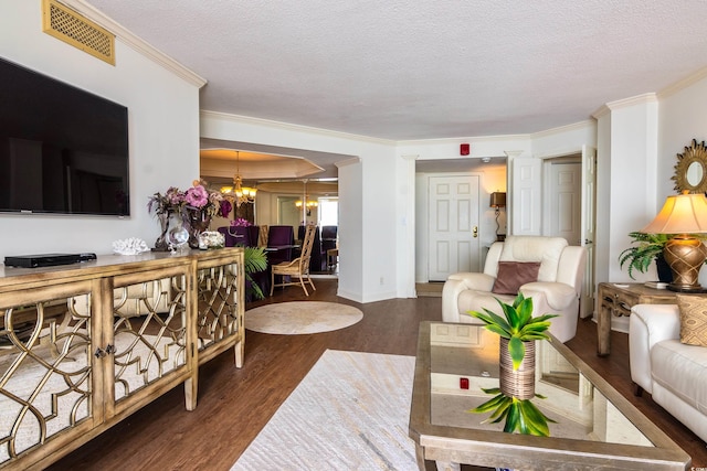 living room featuring crown molding, dark hardwood / wood-style flooring, a textured ceiling, and a notable chandelier