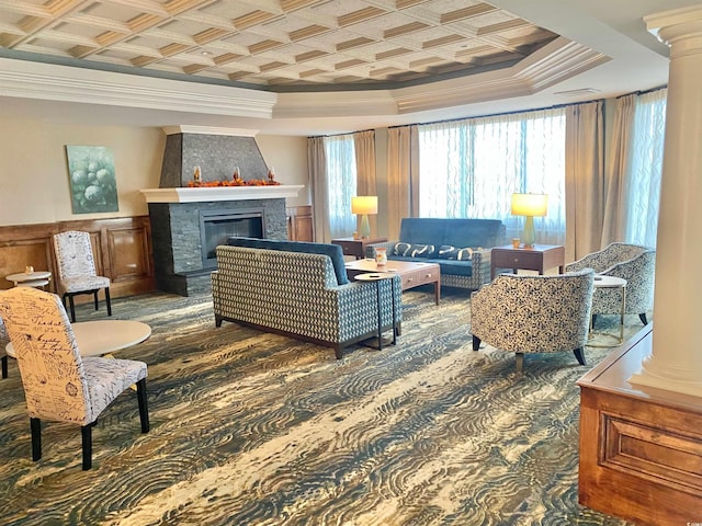 carpeted living room with ornate columns, coffered ceiling, a large fireplace, a raised ceiling, and crown molding