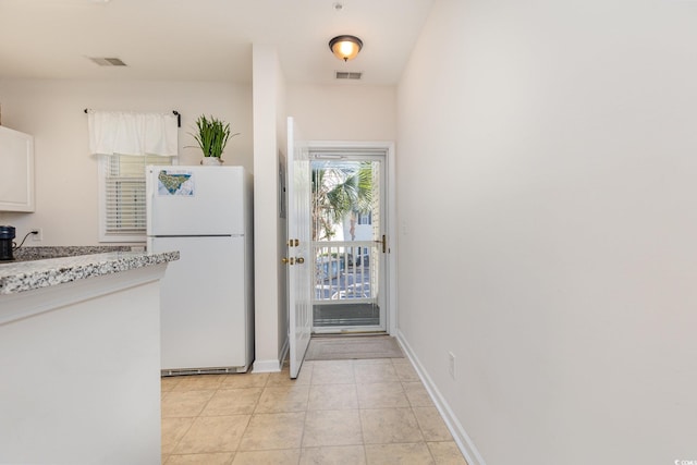 kitchen featuring light tile patterned floors, white fridge, and white cabinetry