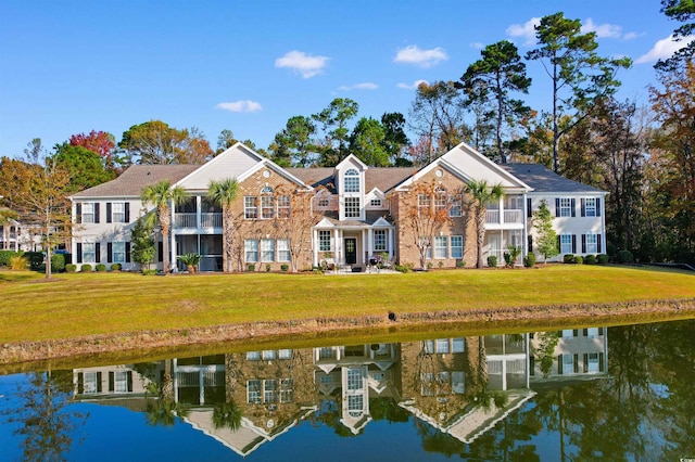 back of house with a lawn and a water view