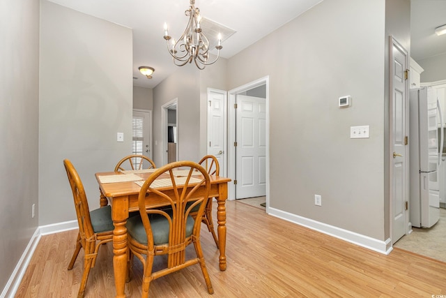 dining space with a notable chandelier and light hardwood / wood-style flooring