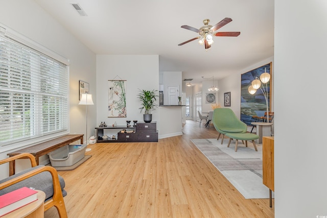 sitting room featuring ceiling fan with notable chandelier and wood-type flooring