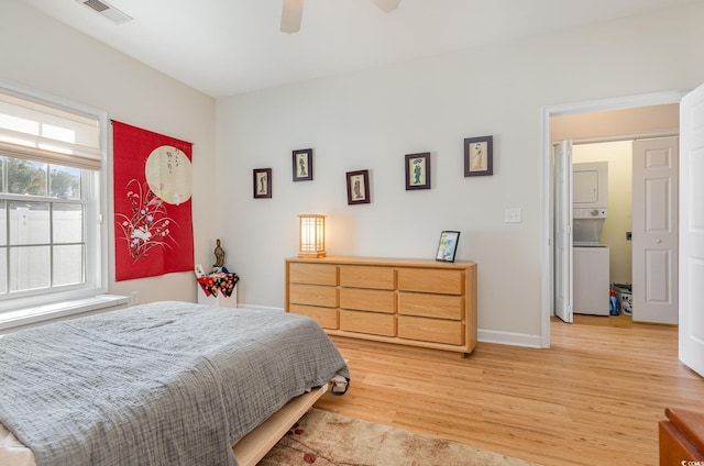 bedroom with stacked washer and dryer, ceiling fan, and light hardwood / wood-style flooring