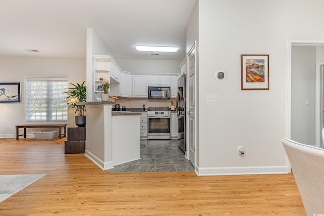 kitchen with stainless steel appliances, light hardwood / wood-style flooring, and white cabinetry