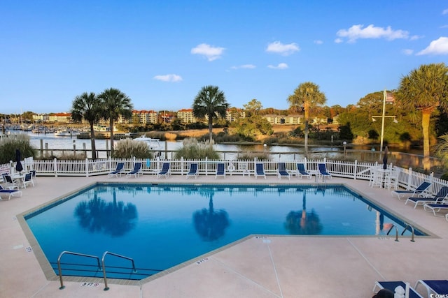 view of pool with a water view and a patio