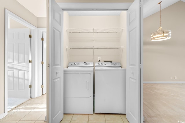 washroom with washer and clothes dryer, light tile patterned floors, and an inviting chandelier