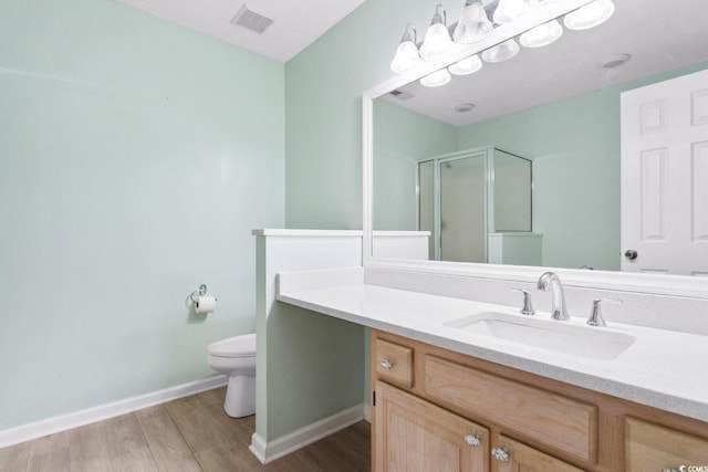 bathroom with toilet, vanity, a shower with shower door, and hardwood / wood-style flooring