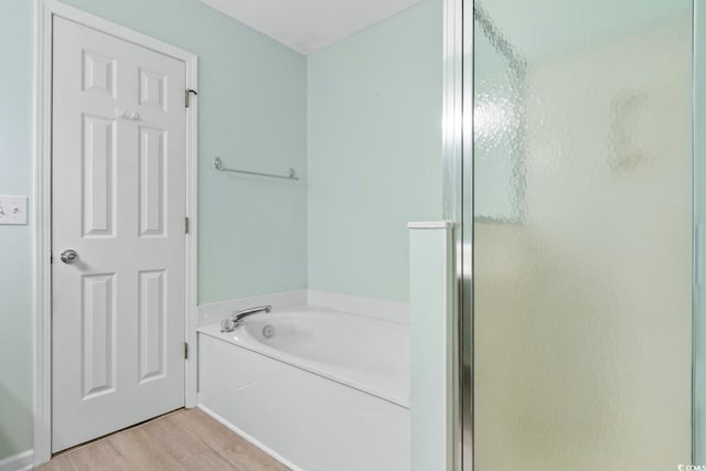 bathroom featuring plus walk in shower and hardwood / wood-style floors