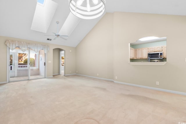 unfurnished living room featuring ceiling fan, light colored carpet, high vaulted ceiling, and a skylight