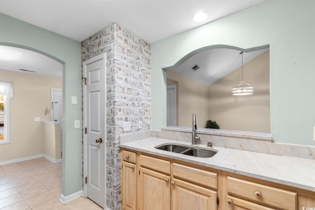 kitchen featuring sink, hanging light fixtures, light stone counters, light brown cabinetry, and light tile patterned floors