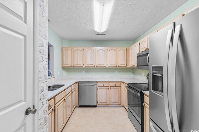 kitchen with sink, light brown cabinets, stainless steel appliances, a textured ceiling, and light tile patterned flooring