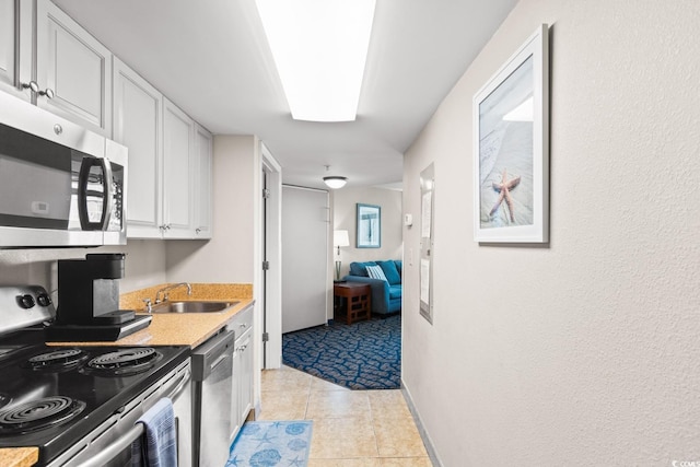 kitchen featuring light tile patterned flooring, stainless steel appliances, white cabinetry, and sink