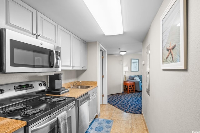 kitchen with white cabinetry, sink, light tile patterned floors, and stainless steel appliances