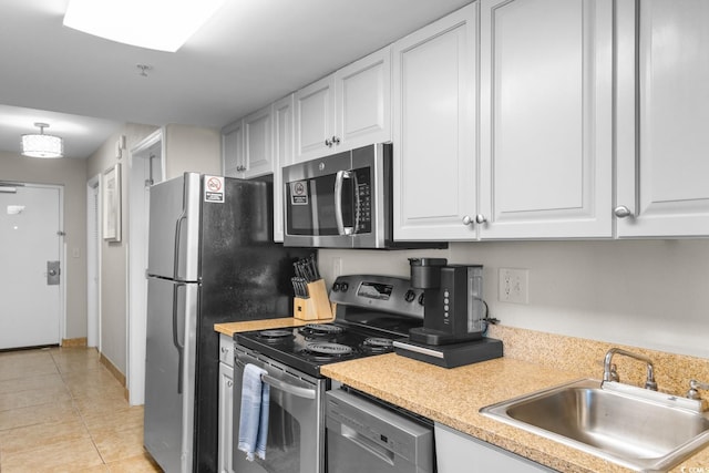 kitchen with white cabinets, stainless steel appliances, light tile patterned flooring, and sink