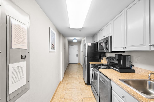 kitchen with white cabinets, sink, light tile patterned floors, and stainless steel appliances