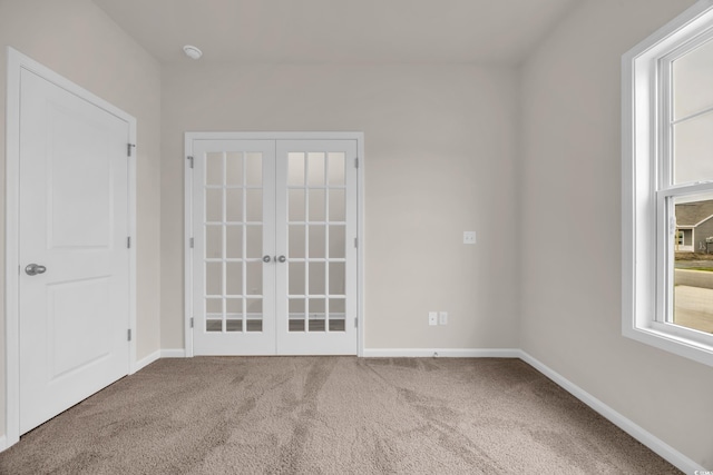 empty room featuring french doors, carpet, and baseboards