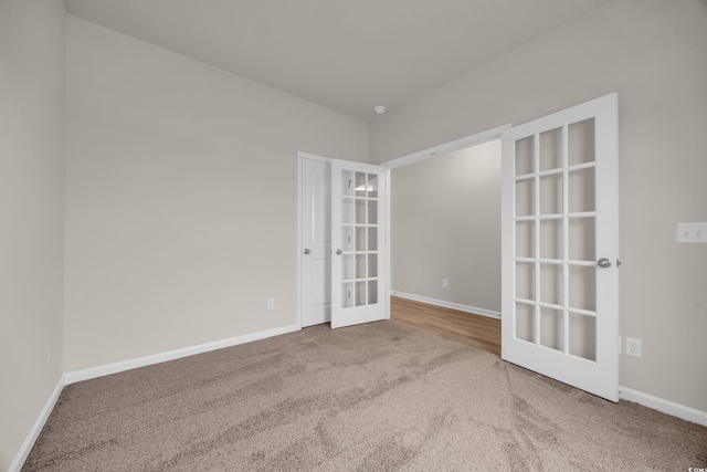 carpeted empty room with french doors and baseboards