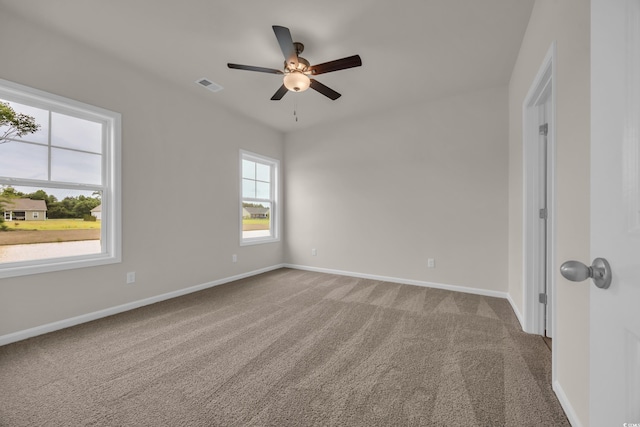 carpeted empty room with a ceiling fan and baseboards