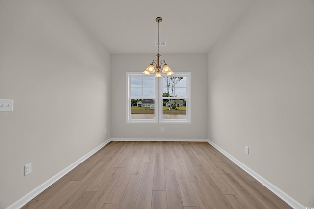 unfurnished room with light wood-style flooring, a chandelier, and baseboards