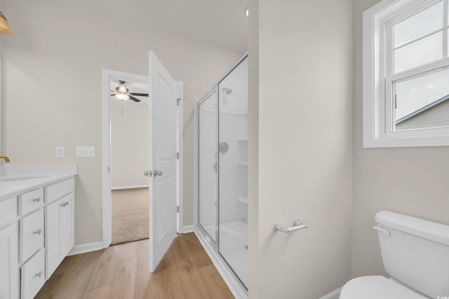 bathroom with wood finished floors, a shower stall, a ceiling fan, and toilet