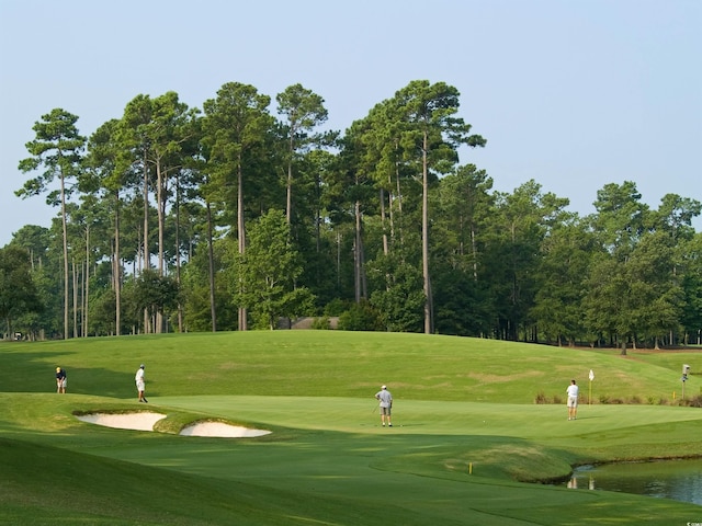 view of community with a yard, golf course view, and a water view