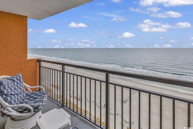 balcony with a water view and a view of the beach