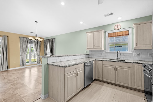 kitchen with kitchen peninsula, appliances with stainless steel finishes, decorative backsplash, light stone counters, and sink