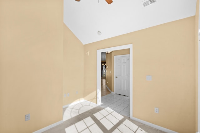 spare room featuring ceiling fan, light carpet, and vaulted ceiling