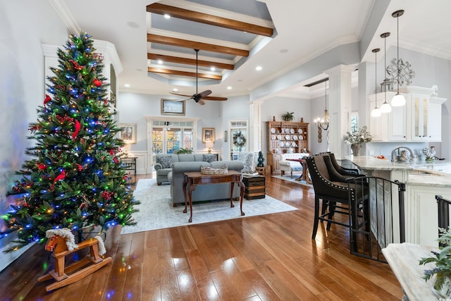 living room with crown molding, light hardwood / wood-style flooring, ceiling fan, beam ceiling, and decorative columns