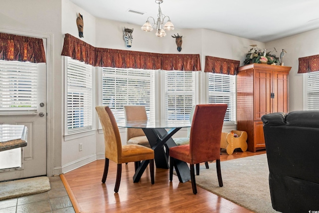 dining space with light hardwood / wood-style floors and a notable chandelier