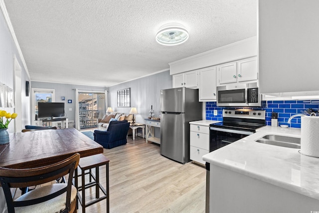 kitchen with sink, crown molding, light hardwood / wood-style flooring, appliances with stainless steel finishes, and white cabinets