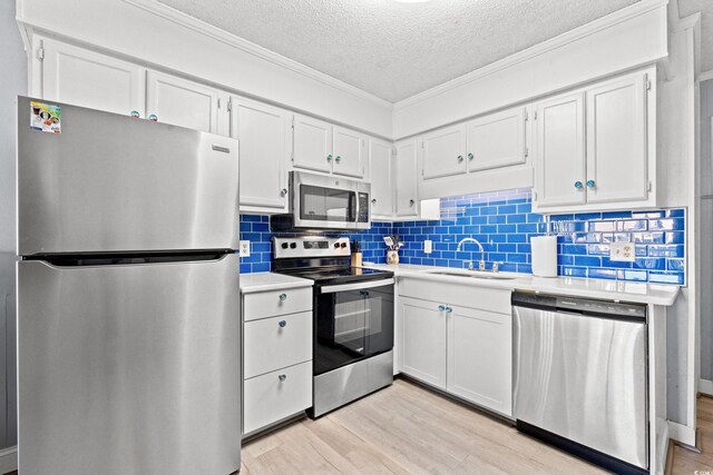 kitchen featuring light wood-type flooring, stainless steel appliances, white cabinetry, and sink