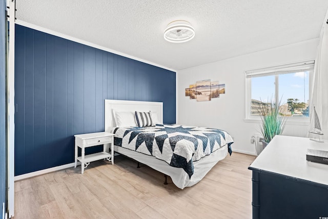 bedroom with ornamental molding, light hardwood / wood-style floors, and a textured ceiling