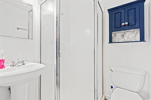 bathroom with sink, a shower with shower door, and toilet