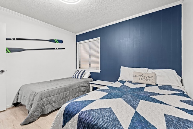 bedroom with ornamental molding, light hardwood / wood-style floors, and a textured ceiling