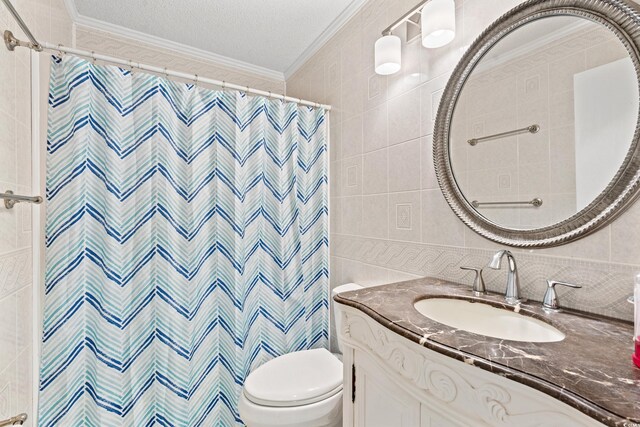 bathroom with vanity, a shower with curtain, toilet, ornamental molding, and tile walls