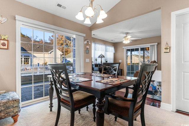 dining space with carpet and ceiling fan with notable chandelier