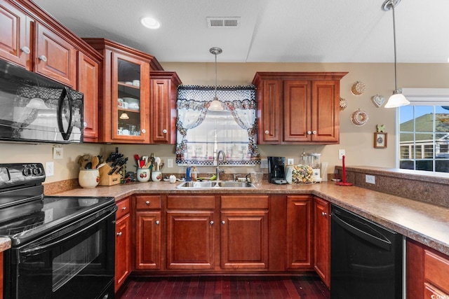 kitchen with hanging light fixtures, sink, black appliances, and dark hardwood / wood-style floors