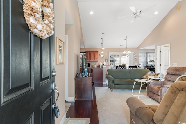 living room with hardwood / wood-style floors, ceiling fan with notable chandelier, and high vaulted ceiling