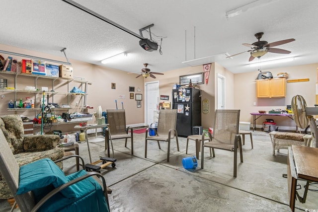 garage with a workshop area, black fridge, ceiling fan, and a garage door opener