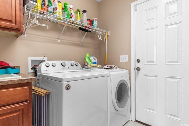 clothes washing area featuring washer and clothes dryer and cabinets